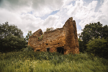 Abandoned building with moody rainy skies and grass blowing in the wind 