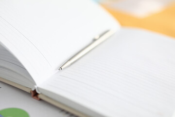 Close-up of notebook with white empty pages and silver pen for writing. Thing for note creative idea and business plan. Blank space on list with thin lines