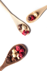 Rustic spoons of Chocolate, Strawberry and Cream Gourmet Popcorn over white background.