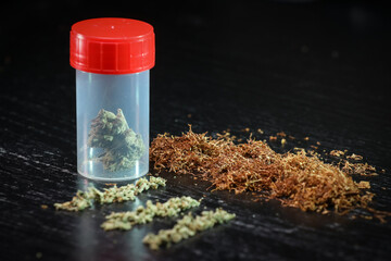 Small box full of cannabis and tobacco on a black background.  Marijuana legalization. Medical...