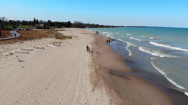 People strolling over the weekend on the waterfront of Lake Michigan in Illinois. View from the drone to the beach and the embankment of the Great Lake.