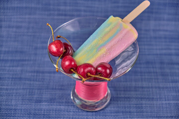 Multi-colored ice cream with ripe red cherries in a beautiful glass vase.Macro.