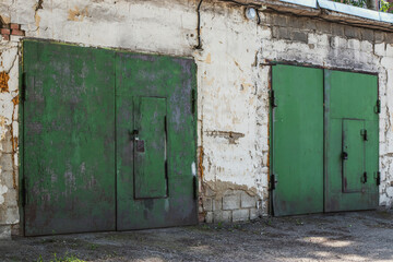 Doors of an old rusty green garage with locks on a summer day. Garage complex in Russia of the twentieth century.
