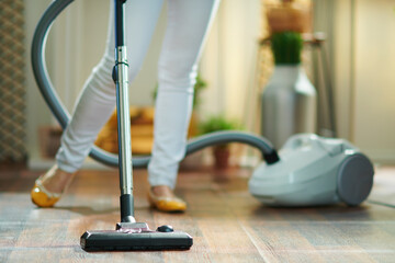 woman in living room in sunny day vacuuming floor