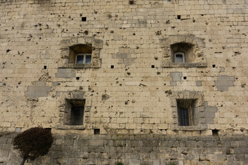 Wall of the ancient European castle with small windows and a lot of gunshots residues. Vintage fortified structure.
