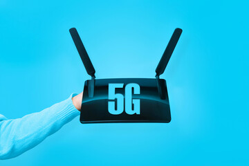 black wifi router on hand and 5G inscription over blue background