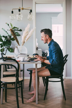 Happy man sitting at table in underwear working at home having a video call
