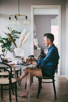 Man sitting at table working from home in underwear