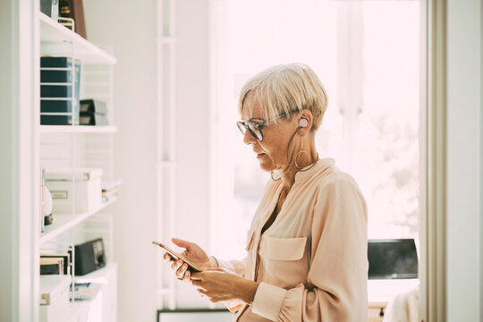 Mature woman using smartphone in home office