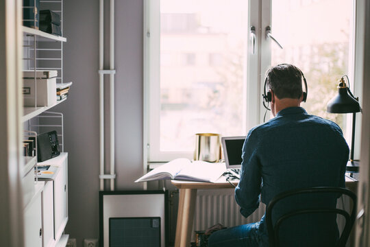 Rear view of man in office at home with headphones