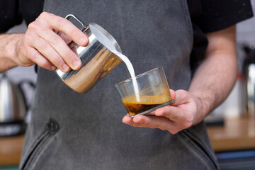 latte art. art of drawing on coffee. barista makes latte art milk from a pitcher