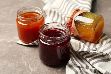 Napkin and glass jars with jam on gray background, close up