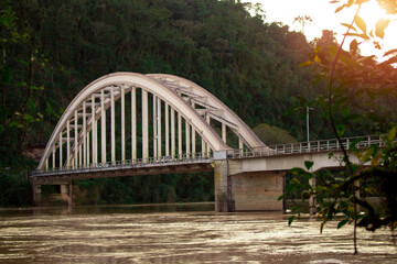 Ponte sobre um rio em uma cidade no interior do Paraná, Brasil.
Ponte velha, com pôr do sol, paisagem verde.