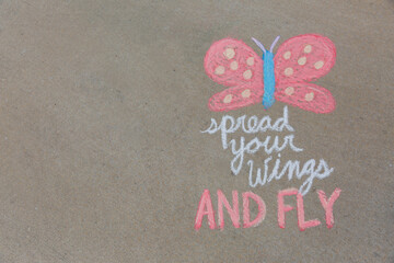 Spread Your Wings and Fly written in sidewalk chalk with a butterfly