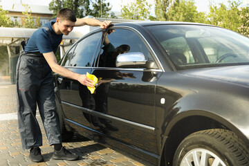 Fototapeta na wymiar A man rubs a car. Car wash. Clear car concept
