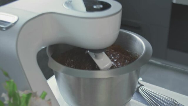 Professional chef is cooking cake. Close up of woman turn on professional mixer with chocalate dought for cake
