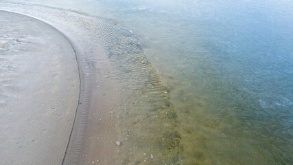 Coastline, melting ice, clear water on the sandy beach.