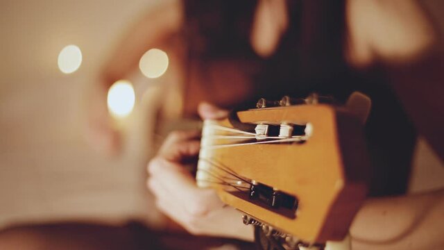 Close up of young girl plays an acoustic guitar at home