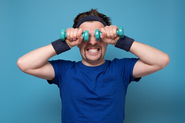 Athletic funny young man doing exercise dumbbell