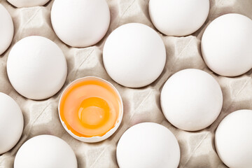 Chicken egg is half broken among other eggs. Top view