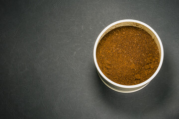 Brown ground coffee in beige jar on the right side with copy-space