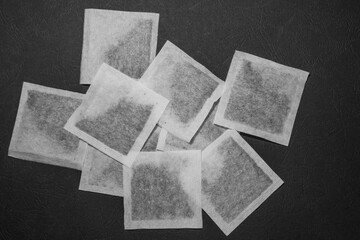 A bunch of square tea bags, lying chaotic on a black background