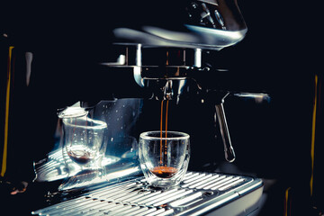 Dark coffee drops dripping in a transparent glass espresso cup on a manual espresso machine with copy space, close up