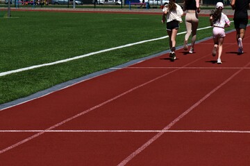 man woman and teen girls run on treadmill of stadium