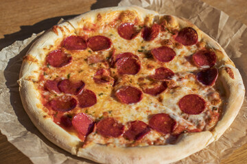 Fragrant classic piperoni pizza in a street cafe is cut into portions. A dish of Italian cuisine.