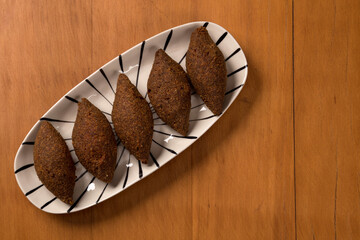 fried kibbeh, served on a plate, on wooden background