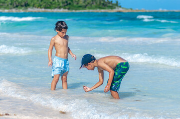 Niños buscan cangrejoes en playa, vacaciones de verano