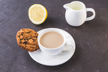 breakfast with tea in white cup with lemon and milk/breakfast with tea in white cup with lemon and milk on a dark table