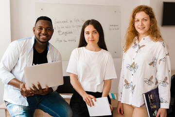Multiethnic students and teacher study foreign languages together in class. Studing with laptop....