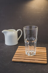 empty glass and white cream/empty glass on a wooden stand and white cream on a dark table