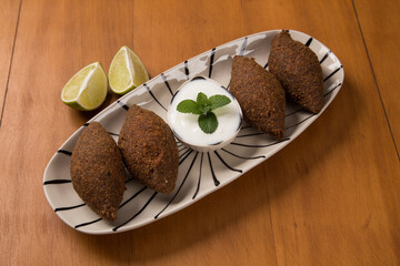 fried kibbeh yogurt sauce served on a white plate