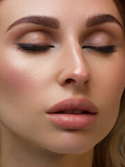 Naklejka premium Close-up portrait of the cleanliness face of a beautiful woman with dark black smoky eyes makeup, natural full lips. Sexy model with clean shiny skin, clean face, long curly hair. glamorous image