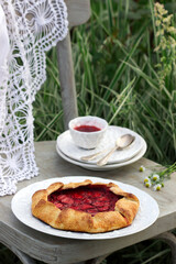Whole grain flour cake stuffed with strawberries with honey sauce on a chair in the garden. Rustic style.