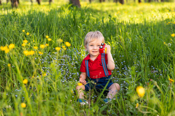 little kid boy playing on grass colored toy