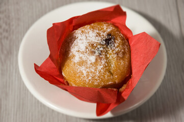Cupcake with cherry filling in a red wrapper on a white ceramic plate. View from above.Sweet dessert.