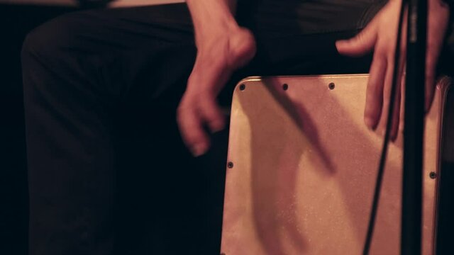 Close-up of a musician in a band performing music with flamenco cajon