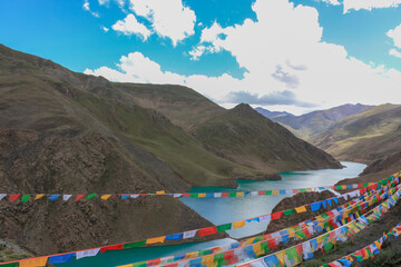Mountain holy lake in Tibet with prayer flags- view from the highway on the way from Lhasa to Kailash, Tibet, Asia