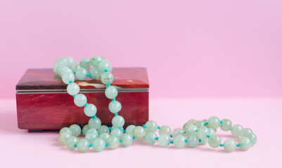 green agate necklace on a gem stone jewelry box on pink background
