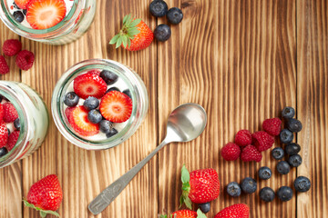 Yogurt pots with berries, strawberries, blueberries and raspberries on a wooden table