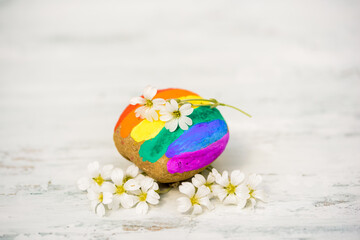 Kindness and hope.Sign be kind and a rainbow on a painted rock. blurred spring blue flowers in the background. love and tolerance, anti racism inclusivness. Gay parade and lesbian shemales