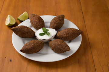 fried kibbeh yogurt sauce served on a white plate