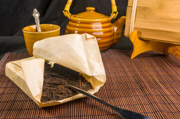 Chinese pressed PU-erh tea on wrapping paper and tea accessories on a bamboo Mat, close-up, macro