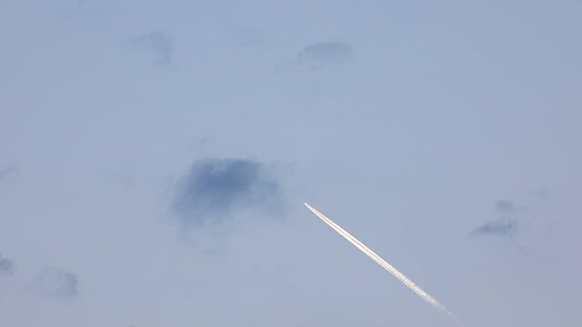 The plane in the blue sky leaving a silver trail pierces the cloud