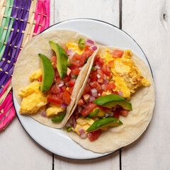 Breakfast egg tacos with flour tortilla and fresh sauce on white background
