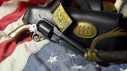 Civil War artifacts including a hat, pistol, sword and belt used by the Union Army on top of an American flag - Powered by Adobe