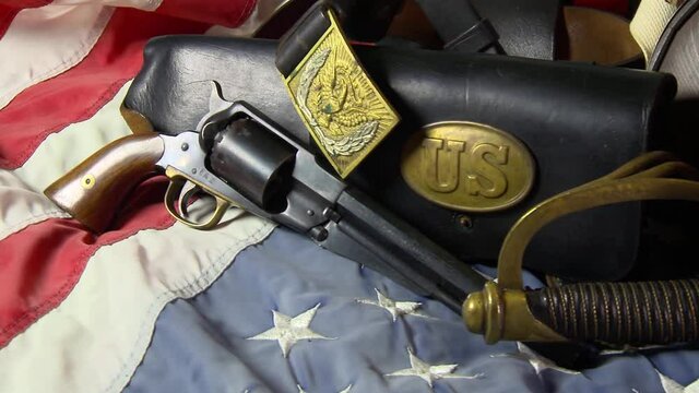 Civil War artifacts including a hat, pistol, sword and belt used by the Union Army on top of an American flag
